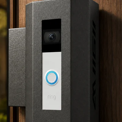 Metal housing around a doorbell, bracket wrapping the edge of the door